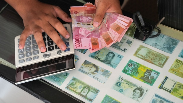A worker counts Indonesian rupiah banknotes at a currency exchange office in Tanggerang, Banten, Indonesia. Photographer: Dimas Ardian/Bloomberg