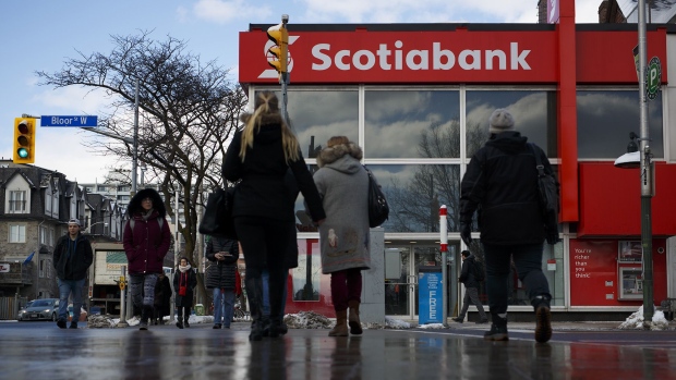 Pedestrians pass in front of a Bank of Nova Scotia branch in Toronto, Ontario, Canada. Photographer: Cole Burston/Bloomberg