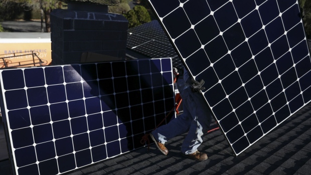 A worker installs solar panels on the rooftop of a home in Poway, California. Photographer: Sandy Huffaker/Bloomberg