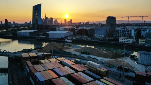 Shipping containers on a barge at Frankfurt Osthafen container port dock near skyscrapers on the financial district skyline, at sunset in the financial district in Frankfurt, Germany, on Tuesday, April 20, 2021. Financial markets around the world are waking up to the risks of another coronavirus flare-up. Photographer: Alex Kraus/Bloomberg