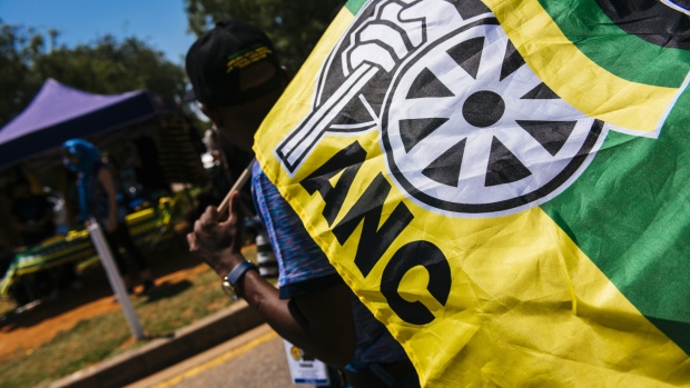 A pedestrian carries an ANC flag during the 54th national conference of the African National Congress party in Johannesburg, South Africa, on Sunday, Dec. 17, 2017. The leadership conference of South Africa’s ruling African National Congress party has accepted the credentials of the delegates, opening the way for the start of voting to choose the party’s top officials, according to five people familiar with the deliberations. 