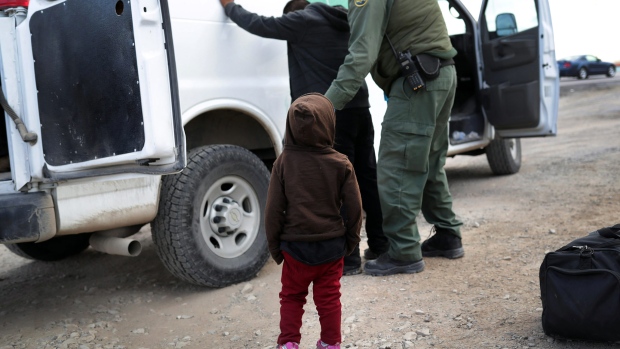 EL PASO, TEXAS - FEBRUARY 01: A child watches as a U.S. Border Patrol agent searches a fellow Central American immigrant after they crossed the border from Mexico on February 01, 2019 in El Paso, Texas. The migrants had turned themselves in, seeking political asylum in the United States. (Photo by John Moore/Getty Images) Photographer: John Moore/Getty Images North America