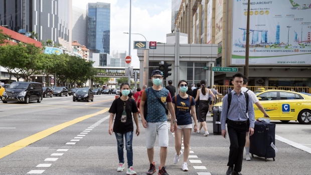 Pedestrians wearing protective masks cross a road in the Chinatown area of Singapore on Friday, Jan. 31, 2020. "We are working hard with MTI and the other agencies on suitable measures to help businesses, Singaporeans, and the economy see through this crisis period," Singapore Prime Minister Lee Hsien Loong told reporters in comments published on an official website. Photographer: Wei Leng Tay/Bloomberg