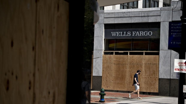 A pedestrian wearing a protective mask walks past a boarded up Wells Fargo bank branch. Photographer: Andrew Harrer/Bloomberg