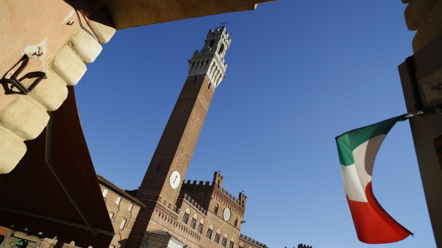 The Italian national flag flies in an entrance to the Piazza del Campo with the Torre del Mangia in the distance, in Siena, Italy, on Friday, Aug. 5, 2016. Banca Monte dei Paschi di Siena SpA's plan to offload $31 billion in doubtful loans, designed to attract investors to a share sale by reducing the bank's risk of losses, will still leave it with a bad-debt level considered unsafe by industry standards.