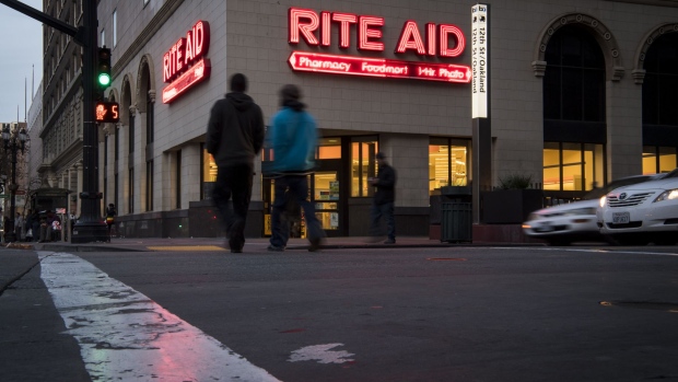 Pedestrians cross a street in front of a Rite Aid Corp. store in Oakland, California, U.S., on Friday, Dec. 29, 2017. Rite Aid Corp. is scheduled to release earnings figures on January 3.