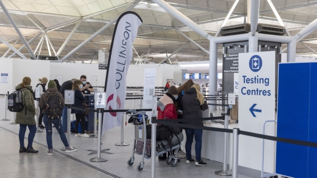 Passengers queue for a walk-through Coronavirus testing centre at London Stansted Airport, operated by Manchester Airport Plc,in Stansted, U.K., on Monday, Jan. 10, 2022. The U.K. will no longer require vaccinated travelers to take a Covid-19 test before boarding a flight to the country, after airlines hard-hit by the omicron variant lobbied for the rules to be eased.