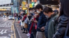 Commuters look at smartphones while standing on a bus-stop in Hong Kong, China, on Friday, Feb. 4, 2022. Hong Kong may look to tighten social distancing measures as coronavirus cases balloon and threaten to overwhelm the city’s health-care system.