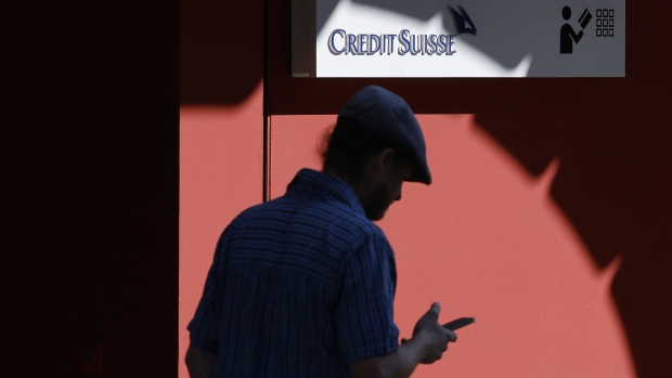 A pedestrian browses a smartphone by a Credit Suisse Group AG bank branch in Zurich, Switzerland, on Thursday, March 24, 2022. Credit Suisse warned it may need to set aside more funds for legal costs as a result of an expected Bermuda court ruling finding it liable for potentially more than $500 million in a case involving a local insurance unit. Photographer: Stefan Wermuth/Bloomberg