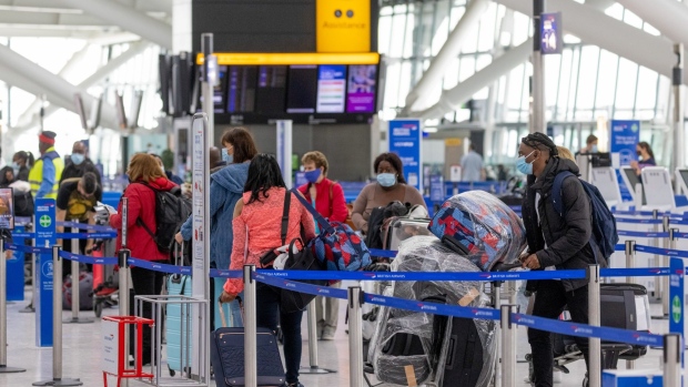 Passengers wait at check-in desks in the airport departures hall in Terminal 5 at London Heathrow Airport.