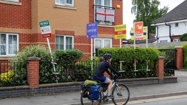 A cyclist passes estate agent "for sale" boards outside a block of flats in Birstall, U.K., on Monday, July 5, 2021. Global valuations in the property markets are soaring at the fastest pace since 2006, according to Knight Frank, with annual price increases in double digits. Photographer: Darren Staples/Bloomberg