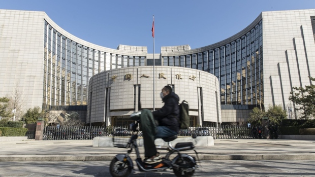 A motorcyclist wearing a protective mask rides past the People's Bank of China (PBOC) building in Beijing, China, on Tuesday, March 17, 2020. China suffered an even deeper slump than analysts feared at the start of the year as the coronavirus shuttered factories, shops and restaurants across the nation, underscoring the fallout now facing the global economy as the virus spreads around the world. Photographer: Qilai Shen/Bloomberg