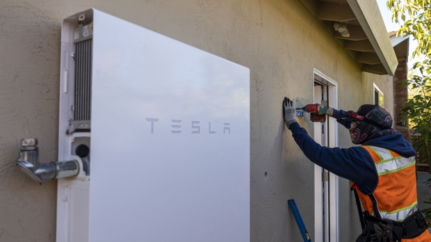 A contractor installs hardware for a Tesla Powerwall battery unit at a home in San Jose, California, U.S., on Monday, Feb. 7, 2022. California regulators are delaying a vote on a controversial proposal to slash incentives for home solar systems as they consider revamping the measure.