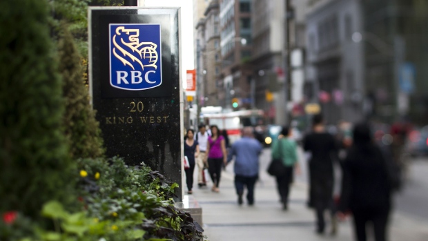 Pedestrians pass in front of RBC Royal Bank signage outside the company's office near Bay Street in Toronto, Ontario.