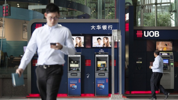 Pedestrians walk past automated teller machines (ATM) at a United Overseas Bank Ltd. (UOB) branch in the central business district (CBD) of Singapore, on Monday, May 27, 2019. UOB's Chief Executive Officer Wee Ee Cheong said he is comfortable going outside his family for a successor to run the lender his grandfather founded more than eight decades ago. Photographer: Ore Huiying/Bloomberg