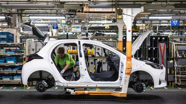 A worker installs components into an automobile on the production line at a Toyota Motor manufacturing plant.