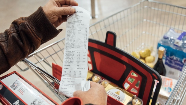 A customer looks at their sales receipt outside a supermarket in Paris.