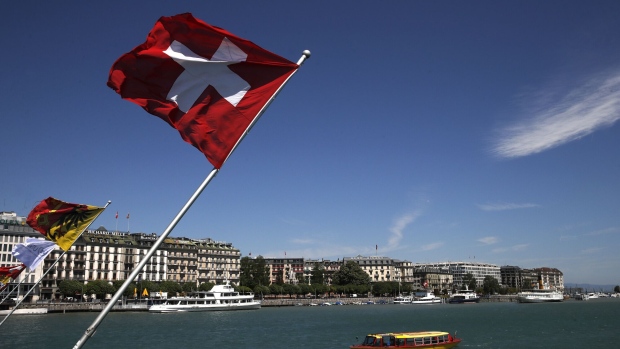 A Swiss national flag flies from the shores of Lake Geneva, also known as Lac Leman, as a ferry boat passes in Geneva, Switzerland, on Tuesday, May 14, 2019. While the Swiss city has largely recovered from the end of secrecy at financial institutions, which shrank the number of banks there by a quarter since 2005, it faces questions about its allure for international businesses and the world’s wealthy. Photographer: Stefan Wermuth/Bloomberg