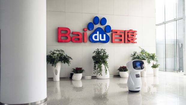 An artificial intelligence (AI) robot in front of the the Baidu Inc. logo at the company's headquarters in Beijing, China, on Thursday, March 4, 2021. Chinese search engine giant Baidu has secured approval from the Hong Kong stock exchange for a second listing in the city, according to people familiar with the matter. Photographer: Qilai Shen/Bloomberg