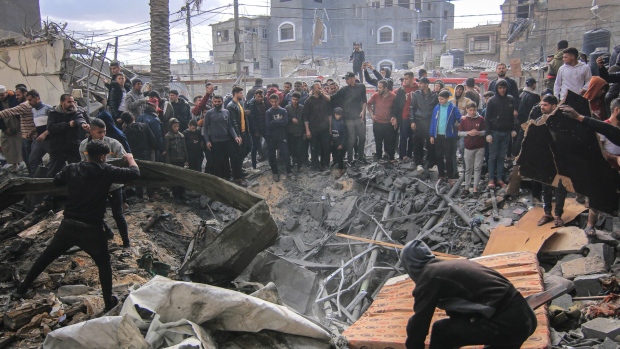 Palestinians search the rubble of buildings destroyed by an Israeli airstrike in Khan Younis, southern Gaza, on Friday, Jan. 12, 2024.