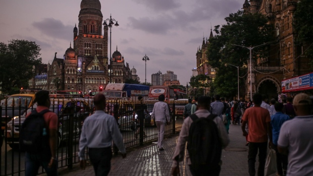 Pedestrians walk towards the Chhatrapati Shivaji Terminus train station at dusk in Mumbai, India.