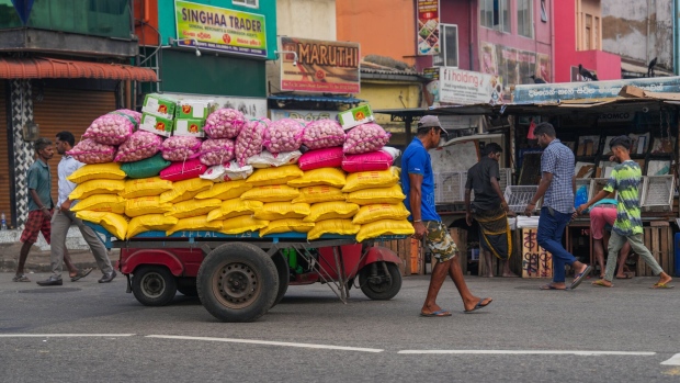 A worker pulls a cart with bags of rice, flour, and garlic in Colombo, Sri Lanka.