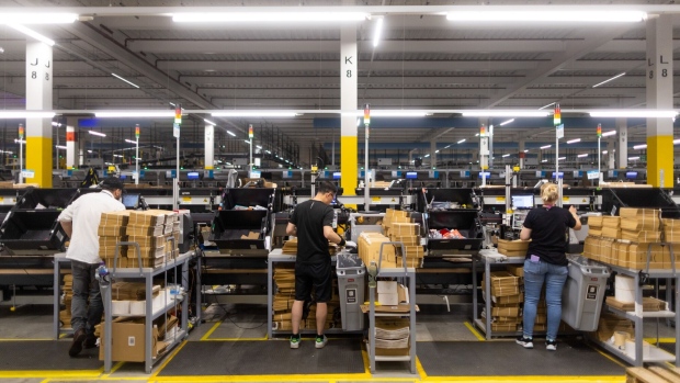 <p>Employees place items in to boxes and envelopes at an Amazon.com Inc. fulfillment center.</p>