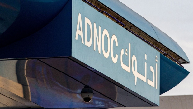 A sign above the forecourt of an Abu Dhabi National Oil Co. (ADNOC) gas station in the Jumeirah district of Dubai, United Arab Emirates, on Thursday, April 20, 2023. Abu Dhabi’s main energy company ADNOC raised $2.5 billion from the initial public offering of its gas business, pulling off the year’s biggest listing and continuing a trend that saw the Middle East emerge as a bright spot for share sales in 2022. Photographer: Christopher Pike/Bloomberg