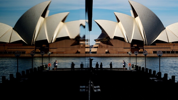 Pedestrians at promenade, opposite the Sydney Opera House, are reflected in a building at The Rocks in Sydney, Australia, on Monday, Aug. 30, 2021. Sydney had a record number of Covid-19 infections, accounting for the bulk of cases in New South Wales as Australia’s most populous state battles to contain the spread of the highly infectious delta variant. Photographer: Brendon Thorne/Bloomberg