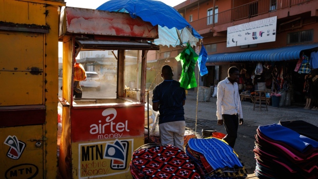 <p>A clothes vendor beside a mobile money transfer kiosk at a market in Lusaka, Zambia.</p>