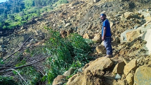 A man stands on rocks at the site of a landslide in Maip Mulitaka in Papua New Guinea's Enga Province on May 24. Photographer: STR/AFP/Getty Images