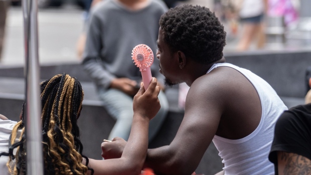 <p>Residents use a handheld fan during a heat wave in New York in 2023.</p>