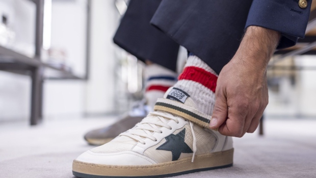<p>A customer tries on a pair of sneakers at a Golden Goose store in London.</p>
