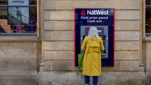 <p>A woman uses an ATM at a bank branch of Natwest in Cardiff, UK.</p>