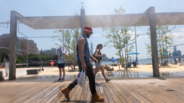 <p>People walk through mist at an artificial beach in Manhattan, on June 21.</p>