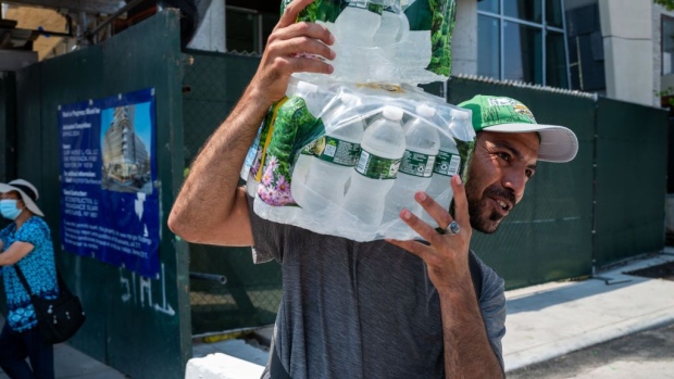 A vendor carries a case of water at Coney Island on a hot afternoon, on June 22.