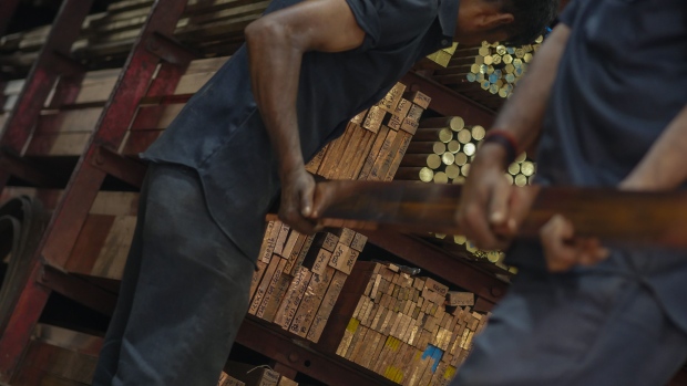 Workers handle a copper bar at a wholesale metal dealer. Photographer: Dhiraj Singh/Bloomberg