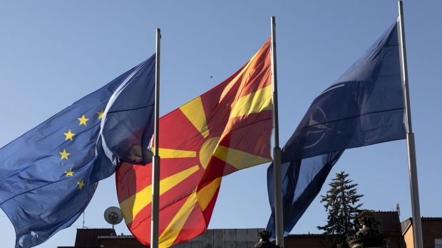 A European Union (EU) flag, left, alongside a North Macedonia national flag, center, and a NATO flag outside a government building during a welcome ceremony of the Bulgarian Prime Minister Kiril Petkov, in Skopje, North Macedonia, on Tuesday, Jan. 18, 2022. North Macedonia’s parliament approved a new government that has vowed to advance negotiations with neighboring Bulgaria in an effort to resolve a bilateral dispute that has blocked accession talks with the European Union. Photographer: Konstantinos Tsakalidis/Bloomberg