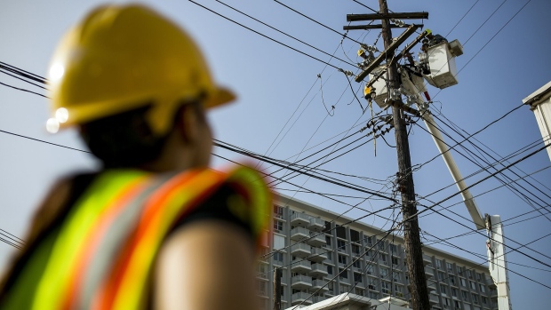 Puerto Rico Electric Power Authority (PREPA) employees fix power lines in Santurce, San Juan, Puerto Rico, on Thursday, Oct. 19, 2017. For longer than most can remember, Puerto Ricans have paid some of the highest energy costs in the U.S. to a notoriously unreliable utility that neglected their grid for years and runs fossil-fuel plants that may be damaging their lungs. A month after Hurricane Maria devastated the island, power lines still lay slack along roads, utility poles are snapped clean in half, and most Puerto Ricans remain in the dark. Photographer: Xavier Garcia/Bloomberg
