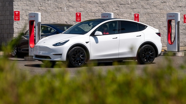 <p>A Tesla vehicle drives past charging stations in Rocklin, California.</p>