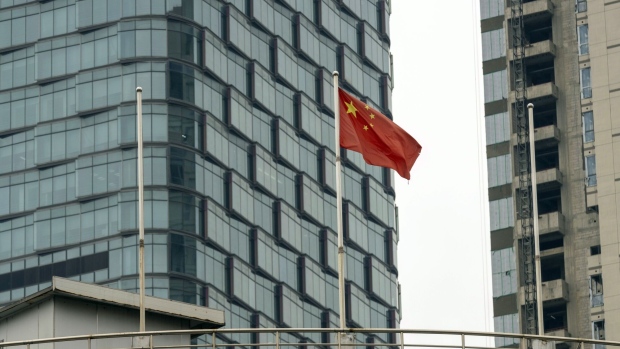 A Chinese flag in front of residential buildings in Shanghai, China, on Monday, June 24, 2024. Shanghai relaxed the cap on prices for new homes, a tactic the government used to temper the property bubble when values were soaring.