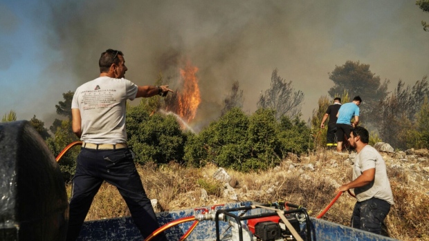 <p>Volunteers work to extinguish a wildfire near Stamata, northeast of Athens, Greece, on June 30.</p>, Photographer: Nick Paleologos/Bloomberg