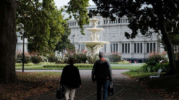 A couple walks through Carlton Gardens in Melbourne, Australia, on Friday, April 5, 2024. Australians have become some of the world’s wealthiest retirement savers in large part because the law that created the super funds also established a steady source of funding. Photographer: James Bugg/Bloomberg