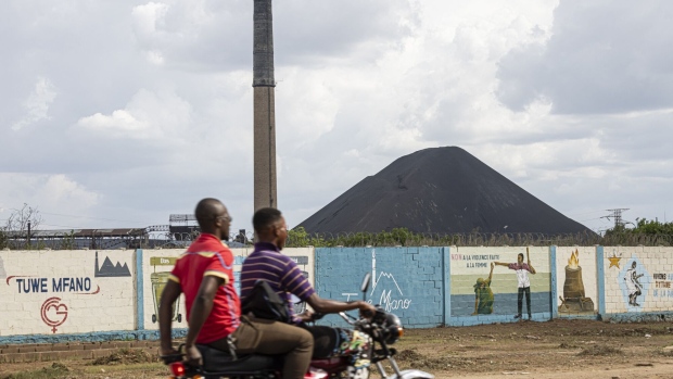 A motorcycle rides past the Gecamines mining complex in Lubumbashi, Democratic Republic of Congo. Photographer: Patrick Meinhardt/AFP/Getty Images