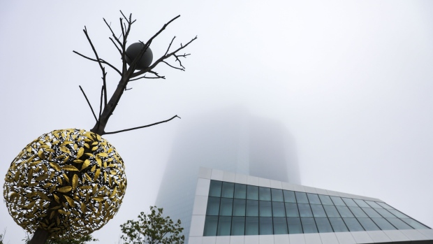 A bronze and granite tree-shaped sculpture entitled Gravity and Growth stands beside the fog shrouded European Central Bank (ECB) headquarters ahead of a farewell ceremony for ECB President Mario Draghi in Frankfurt, Germany, on Monday, Oct. 28, 2019. Christine Lagarde will inherit two gifts when she takes over the presidency of the European Central Bank, both temporary and both from Draghi. Photographer: Alex Kraus/Bloomberg