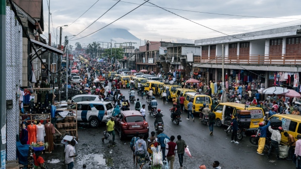 <p>Shoppers and pedestrians pass lines of taxis and stores at Birere market in Goma, Democratic Republic of Congo.</p>
