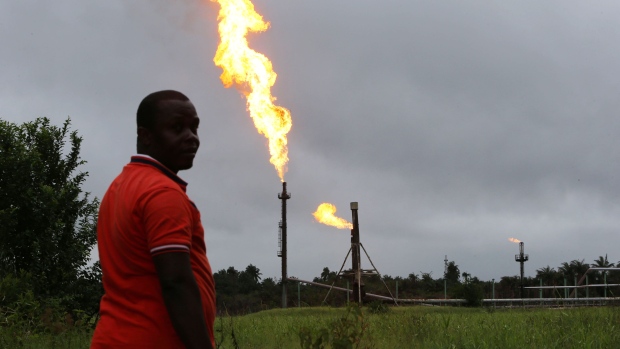 A man looks on as flares burn from pipes at an oil flow station operated by Nigerian Agip Oil Co. Ltd. (NAOC), a division of Eni SpA, in Idu, Rivers State, Nigeria, on Monday, Sept. 28, 2015. Nigeria's daily output of about 2 million barrels of oil makes it Africa's largest producer. Photographer: Bloomberg/Bloomberg